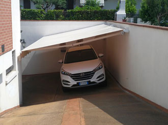 Tenda fissata al muretto per riparare auto